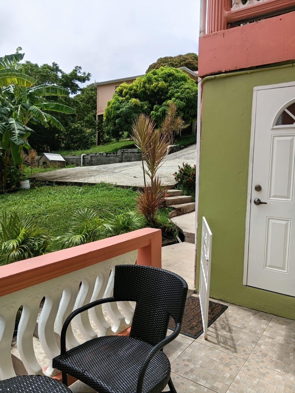 Covered patio with wicker chair looking out over the tropical garden and banana trees