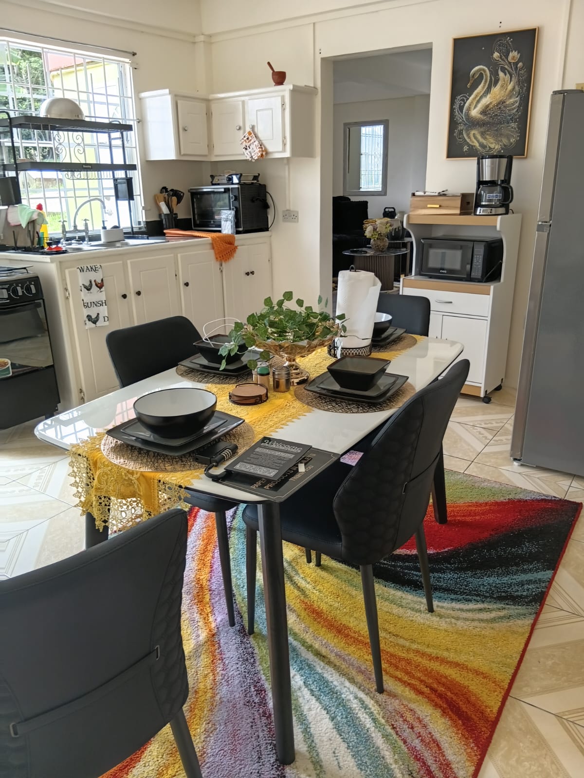 Open kitchen and dining table set for four on a colourful rug